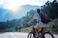 Beautiful young girl rides a bicycle on a beautiful mountain road. Summer holidays and cycling, sports and outdoor activities