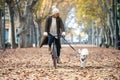 Beautiful young girl riding a bike while walking her dog in the park in autumn Royalty Free Stock Photo