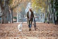 Beautiful young girl riding a bike while walking her dog in the park in autumn Royalty Free Stock Photo