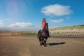 Beautiful young girl riding a Friesian mare on the coast of Hauts-de-France