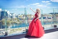 Beautiful young girl on the roof of a building in a red lush dress