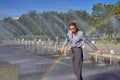 The scared girl in the spray of the fountain on the background of the rainbow Royalty Free Stock Photo