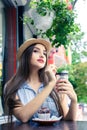 Beautiful young girl in rustic hat drinking coffee in outdoors c Royalty Free Stock Photo