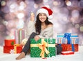 Beautiful young girl in santa hat with glass of champagne and gift boxes Royalty Free Stock Photo