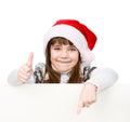 Beautiful young girl with santa hat standing behind white board. isolated on white Royalty Free Stock Photo