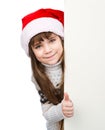 Beautiful young girl with santa hat standing behind white board on white Royalty Free Stock Photo