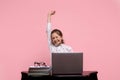 Schoolgirl smiles and does exercises while sitting near a laptop.