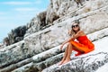 Beautiful young girl by the sea. Woman in a red dress on the beach. Seaside vacation. Rocky terrain Royalty Free Stock Photo