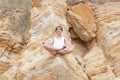 A beautiful young girl with short hair is dressed in shorts and a white jersey is practicing yoga on the background of rocks. Royalty Free Stock Photo