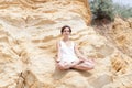 A beautiful young girl with short hair is dressed in shorts and a white jersey is practicing yoga on the background of rocks. Pose Royalty Free Stock Photo