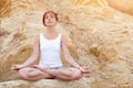 A beautiful young girl with short hair is dressed in shorts and a white jersey is practicing yoga on the background of rocks. Pose Royalty Free Stock Photo