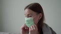 Beautiful young girl shows how to put on a medical mask privately. Orvi, coronovirus, acute respiratory disease.