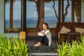 Beautiful young girl sits on the veranda the bungalow near the ocean beach in Bali island Indonesia Royalty Free Stock Photo