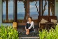 Beautiful young girl sits on the veranda the bungalow in Bali beach Indonesia Royalty Free Stock Photo