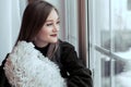 Beautiful young girl sitting alone on the windowsill and looking out the window Royalty Free Stock Photo