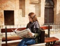 Beautiful young girl sitting on a bench reading the newspaper Royalty Free Stock Photo