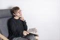 Beautiful young girl is sitting in a chair and holding a book in her hands. woman thoughtfully looks into the distance. Royalty Free Stock Photo