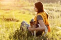 A beautiful young girl is sitting on the grass and hugging her dog. A girl and her pet are resting after a walk in nature. Friend