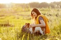 A beautiful young girl is sitting on the grass and hugging her dog. A girl and her pet are resting after a walk in nature. Friend