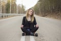 Beautiful young girl sitting in the middle of the road. Royalty Free Stock Photo