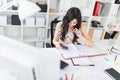 Beautiful young girl sitting at an office desk holding a pen in her mouth and looking into the calculator. Royalty Free Stock Photo