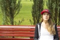 Beautiful young girl sitting on a park bench.