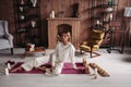 Beautiful young girl sitting relaxing on mat with candles in stylish cozy comfort home interior with comfy furniture Royalty Free Stock Photo