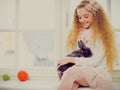 Beautiful young girl sitting on a windowsill and playing with Easter bunny. Royalty Free Stock Photo