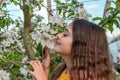 Beautiful young girl smelling a twig of blooming plum flowers in a sunny spring day Royalty Free Stock Photo