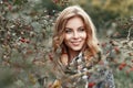 Beautiful young girl with a smile in a warm scarf near a tree