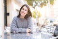 Beautiful young girl smiling cheerful sitting on a cafeteria, relaxing and enjoying sunlight at the town