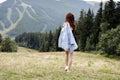 A beautiful young girl stands against the background of the mountains in the summer. Beautiful landscape of mountains Royalty Free Stock Photo