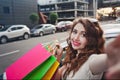 Beautiful young girl stands near a white car, makes a shopping, selfie Royalty Free Stock Photo