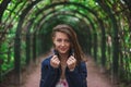 Beautiful and young girl stands under colorful plant archway in the green park