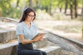 Beautiful young girl studying on a tablet on a park background. Self-education concept. Copy space. Royalty Free Stock Photo