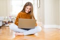 Beautiful young girl studying using laptop sitting on the floor at home with a happy face standing and smiling with a confident Royalty Free Stock Photo