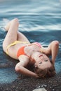 Beautiful young girl in swimsuit, posing lying on the beach Royalty Free Stock Photo