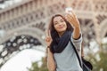 Beautiful young girl taking funny selfie with her mobile phone near the Eiffel tower. Royalty Free Stock Photo