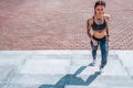 Beautiful young girl in tattoos, summer city, hand smartphone listens music headphones, sportswear, leggings and bra Royalty Free Stock Photo