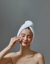 Beautiful young girl with towel on head hold cotton pad cleansing face skin remove makeup, enjoy skincare beauty routine Royalty Free Stock Photo