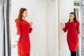 Beautiful young girl trying on a red dress in the store. Pretty woman posing near the whim Royalty Free Stock Photo