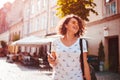 Beautiful young girl using smartphone and listening to the music walking on street. Woman dancing and singing Royalty Free Stock Photo