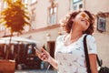 Beautiful young girl using smartphone and listening to the music walking on street. Woman dancing and singing Royalty Free Stock Photo