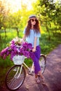 Beautiful young girl with vintage bicycle and flowers on city background in the sunlight outdoor. Royalty Free Stock Photo