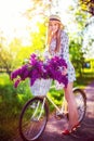 Beautiful young girl with vintage bicycle and flowers on city background in the sunlight outdoor. Royalty Free Stock Photo