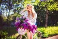 Beautiful young girl with vintage bicycle and flowers on city background in the sunlight outdoor. Royalty Free Stock Photo