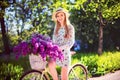 Beautiful young girl with vintage bicycle and flowers on city background in the sunlight outdoor. Royalty Free Stock Photo