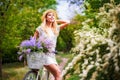 Beautiful young girl with vintage bicycle and flowers on city background in the sunlight outdoor. Royalty Free Stock Photo