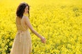 Beautiful young girl walking in the yellow canola field, touching flowers with her hand. Model dressed in beige dress relaxing Royalty Free Stock Photo