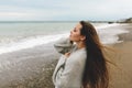 A beautiful young girl walks along the seashore, a storm, hair fly apart, a gray cardigan, a sports figure in sneakers Royalty Free Stock Photo